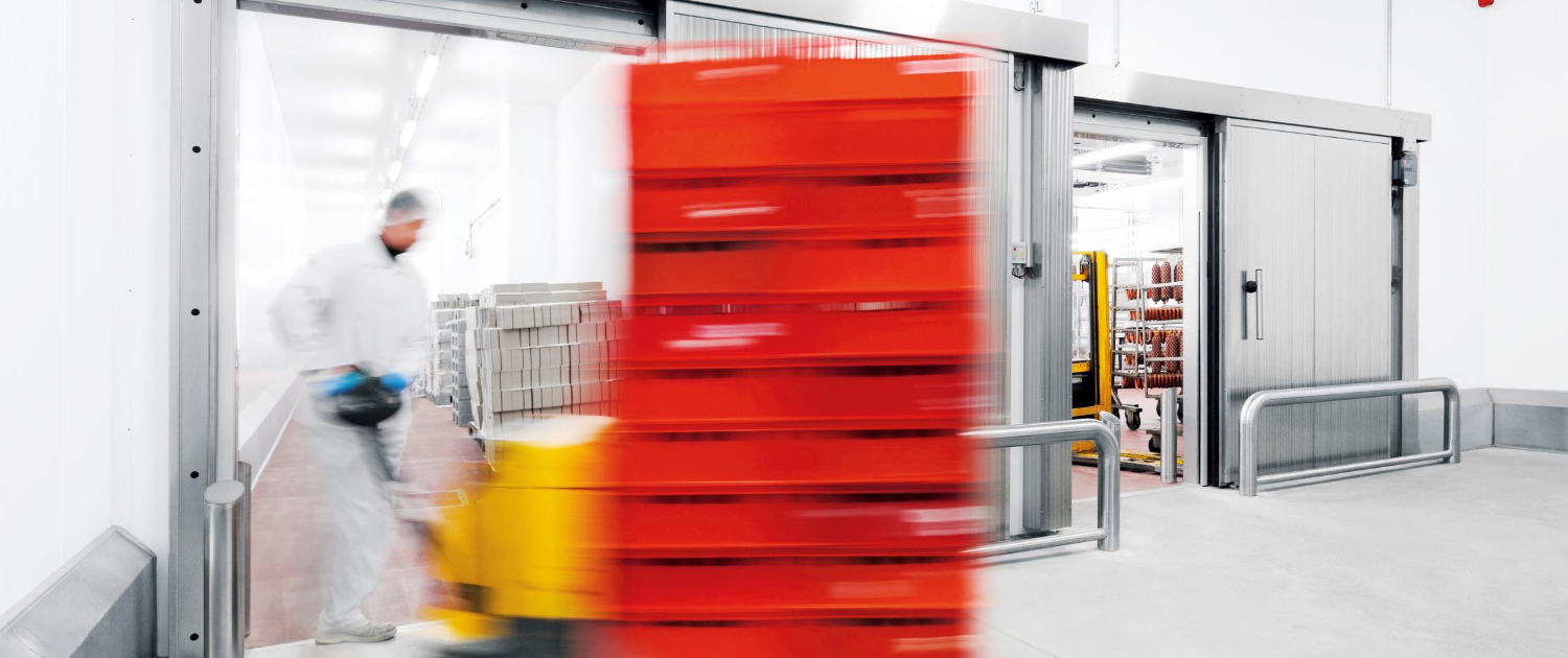 Gabelhubwagen transportiert rote Kisten durch eine Industrie-Kälte­schutztür